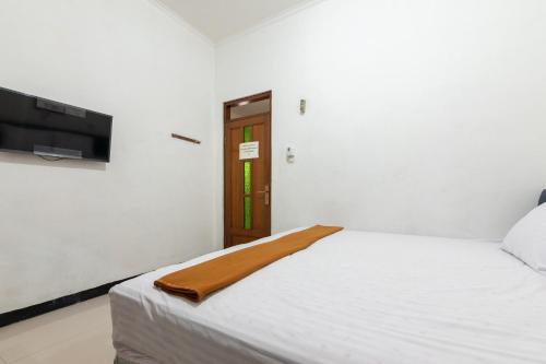 a bedroom with a white bed and a flat screen tv at House Of M Bogor Mitra RedDoorz in Bantarkamang