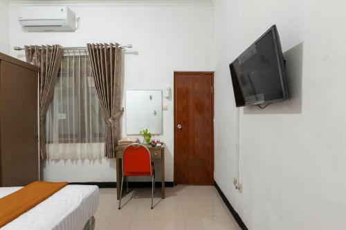 a room with a bed and a television on a wall at House Of M Bogor Mitra RedDoorz in Bantarkamang
