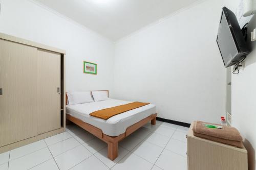 a small bedroom with a bed and a television at House Of M Bogor Mitra RedDoorz in Bantarkamang