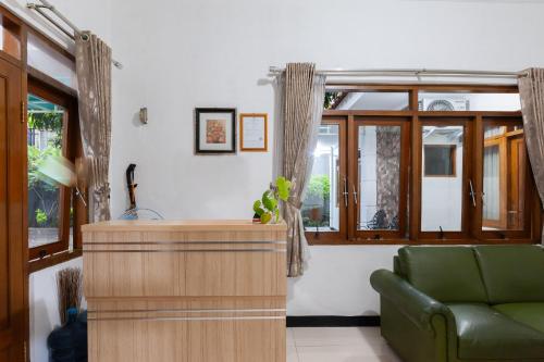 a living room with a green couch and a window at House Of M Bogor Mitra RedDoorz in Bantarkamang
