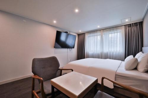 a hotel room with a bed and a couch and a tv at Anyang ILLOWA Hotel in Anyang
