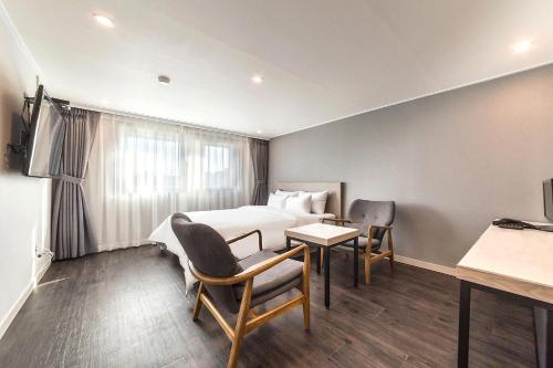 a hotel room with a bed and a table and chairs at Anyang ILLOWA Hotel in Anyang
