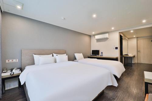a bedroom with two beds and a desk and a television at Anyang ILLOWA Hotel in Anyang
