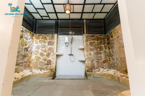 a bathroom with a shower with a stone wall at Koh Rong Hill Beach Resort in Koh Rong Island