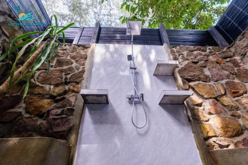 a shower in a bathroom with a stone wall at Koh Rong Hill Beach Resort in Koh Rong Island