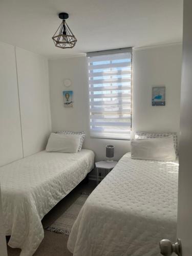 Duas camas num quarto branco com uma janela em descanso y paz em Caldera