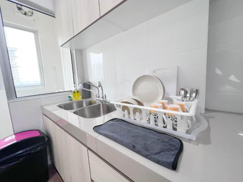 a white kitchen with a sink and a dishwasher at Maison Signature Suites in Kuala Lumpur