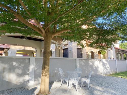 a table and chairs under a tree in front of a house at Kuala Terengganu Newly Renovated Nenda Beach House in Kuala Terengganu