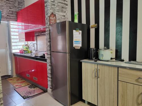 uma cozinha com um frigorífico de aço inoxidável e armários vermelhos em Teratak Delisha -musslim em Kampong Jemampar