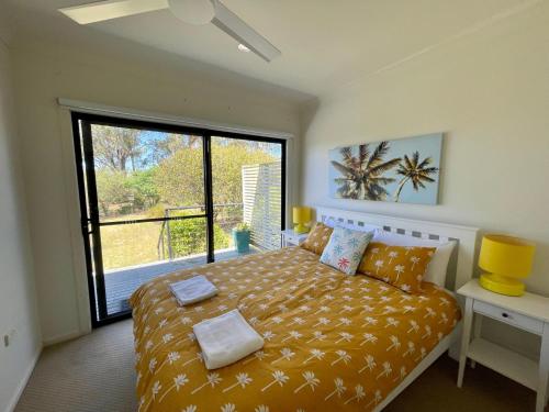 a bedroom with a bed and a large window at Sea Breeze on Carroll - 4BR beachside home in Mollymook