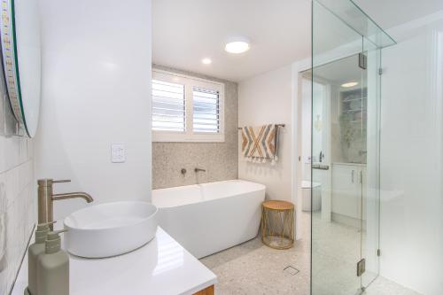 a white bathroom with a tub and a sink at Hastings Cove Holiday Apartments in Hastings Point