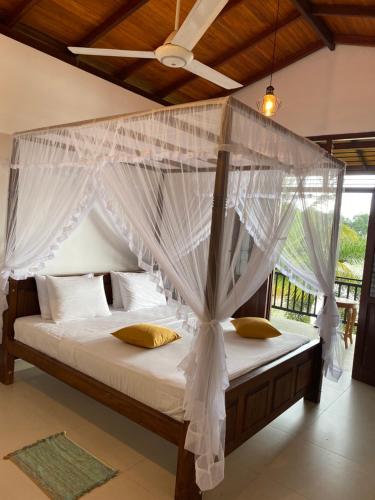 1 dormitorio con cama con dosel y cortinas blancas en Villa Lake Mountain, en Weligama
