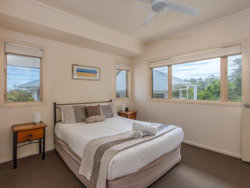 a bedroom with a bed and two windows at Hastings Cove Holiday Apartments in Hastings Point
