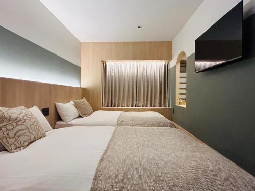 a bedroom with two beds and a flat screen tv at HOTEL KANMA UENO in Tokyo