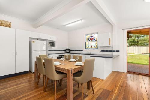 a kitchen and dining room with a wooden table and chairs at Campbell's Cottage by Experience Jervis Bay in Huskisson