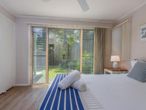 a bedroom with a large bed and a large window at Hastings Cove Holiday Apartments in Hastings Point