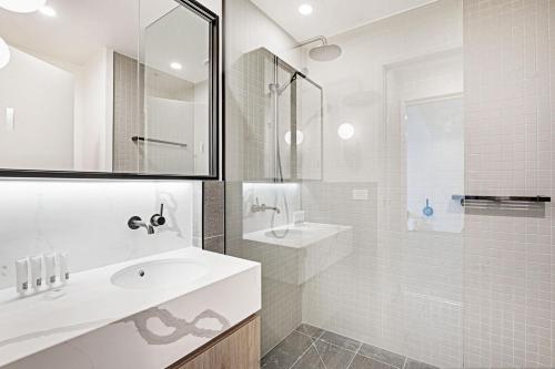 a white bathroom with a sink and a shower at Lumina Suites in Melbourne