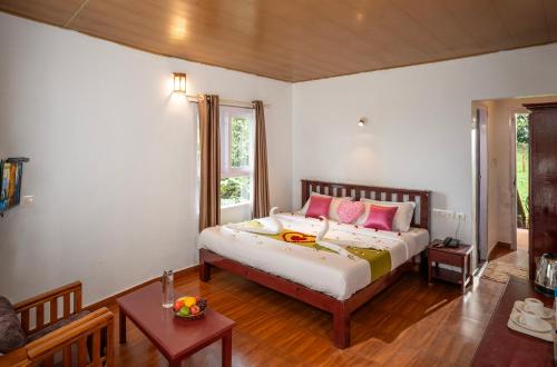 Schlafzimmer mit einem Bett mit rosa und gelben Kissen in der Unterkunft Blue Bells Resort By Maat Hotels in Munnar