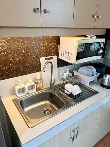 a kitchen counter with a sink and a microwave at Oasis Homestay (One Oasis Condominium) in Davao City