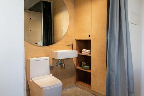 a bathroom with a toilet and a sink and a mirror at HomeBase Kapitolyo - Minimalist Serviced Apartments in Manila