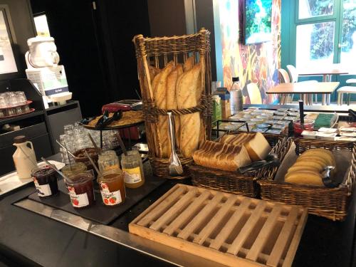 stół z koszami chleba i innego jedzenia w obiekcie KYRIAD HONFLEUR - La Riviere Saint Sauveur w mieście Honfleur