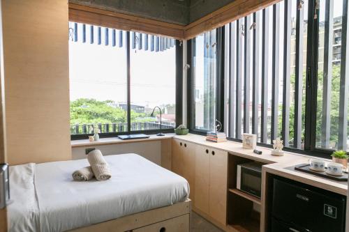a bedroom with large windows and a bed with pillows at HomeBase Kapitolyo - Minimalist Serviced Apartments in Manila