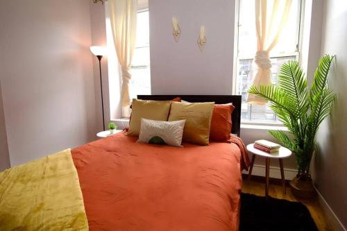 een slaapkamer met een oranje bed met kussens en een plant bij Tuk Ahoy - Cozy Condo Apartment in Brooklyn