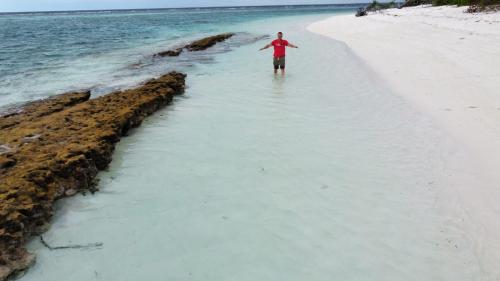 a man standing in the water on a beach at Boegas View Guesthouse in Vaikaradhoo