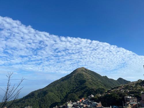 a mountain under a blue sky with clouds at Yu Apartment in Jiufen