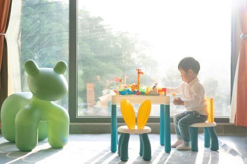 a young child playing with a toy table and chairs at Phoenix Best River View B&B in Fenghuang