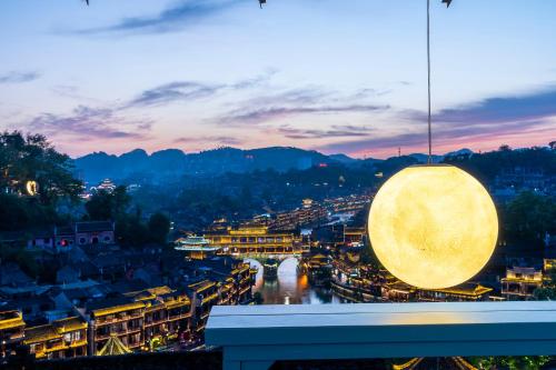 a view of a city at night with a light fixture at Phoenix Best River View B&B in Fenghuang
