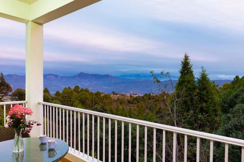a balcony with a table and a view of the mountains at Morning Bliss by VEO - Part of StayVista in Rānīkhet