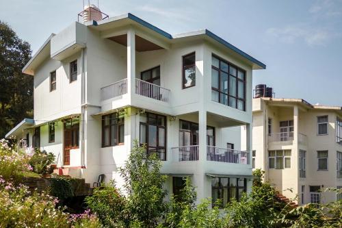 a white building with a clock on top of it at Morning Bliss by VEO - Part of StayVista in Rānīkhet