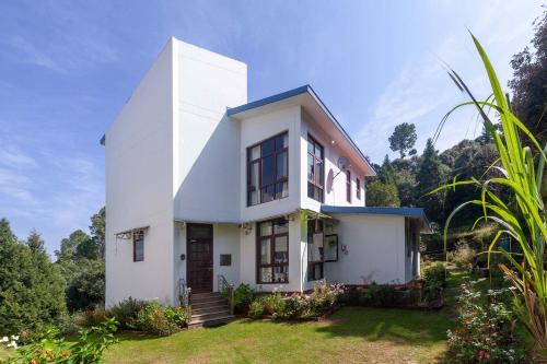 a white house on top of a hill at Morning Bliss by VEO - Part of StayVista in Rānīkhet