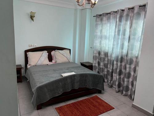 a bedroom with a bed and a window with curtains at Joel House deido in Douala