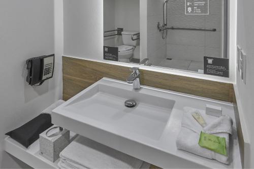 a bathroom with a sink and a toilet and a mirror at City Express Plus by Marriott Tijuana in Tijuana