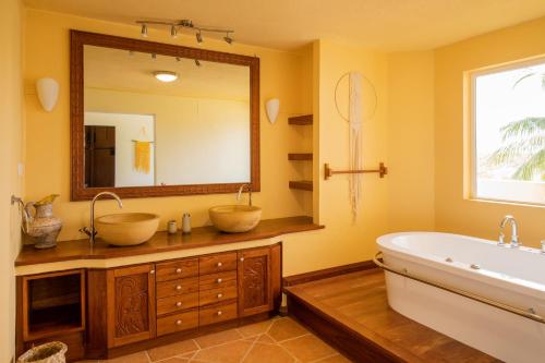 La salle de bains est pourvue de 2 lavabos et d'un grand miroir. dans l'établissement Villa Trankil'O - Villa pieds dans l'eau, Piscine, Kiosque, Barbecue, à Petite Case Noyale