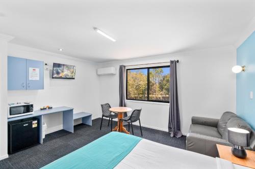 a room with a bed and a couch and a table at Econo Lodge Waterford in Loganlea