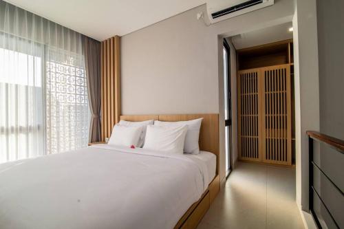 Un dormitorio con una gran cama blanca y una ventana en Anahata Home, en Tabanan