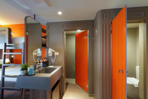 an orange bathroom with a sink and a mirror at Tinidee Trendy Bangkok Khaosan in Bangkok