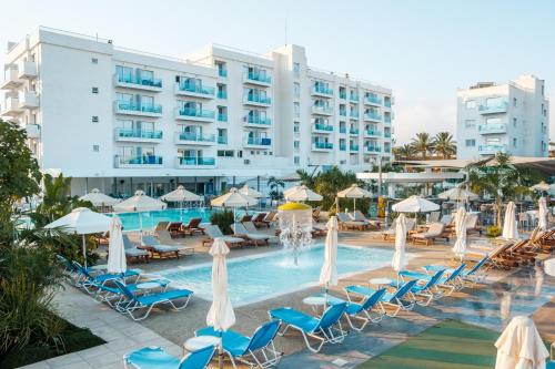 a pool with chairs and umbrellas and a hotel at Kapetanios Bay Hotel Protaras in Protaras