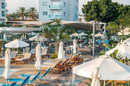 a hotel pool with chairs and umbrellas at Kapetanios Bay Hotel Protaras in Protaras