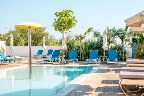 a swimming pool with blue chairs and umbrellas at Kapetanios Bay Hotel Protaras in Protaras