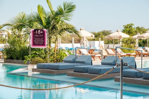 a pool with chairs and a sign in the water at Kapetanios Bay Hotel Protaras in Protaras