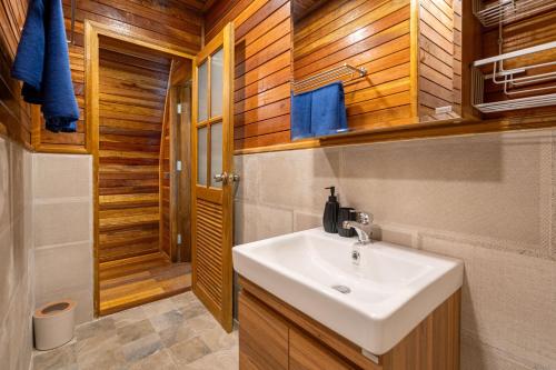 a bathroom with a sink and a shower with wooden walls at New 3BR Chalet-Style Villa Pasak Paradise 3, Private Pool, 10min grive to Laguna Phuket in Ban Pak Lak