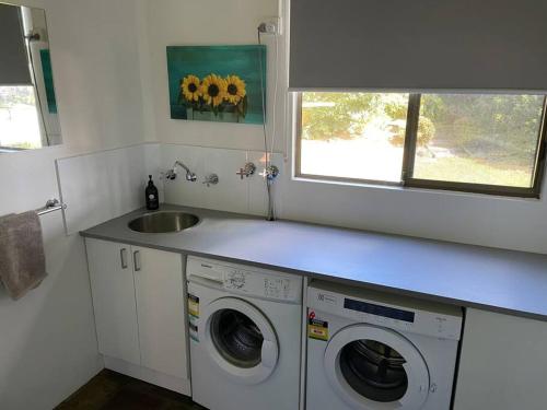 a kitchen with a washing machine and a sink at Gerroa Beach Family Headland Escape in Gerroa