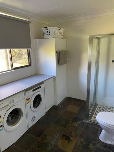 a bathroom with a washing machine and a toilet at Gerroa Beach Family Headland Escape in Gerroa