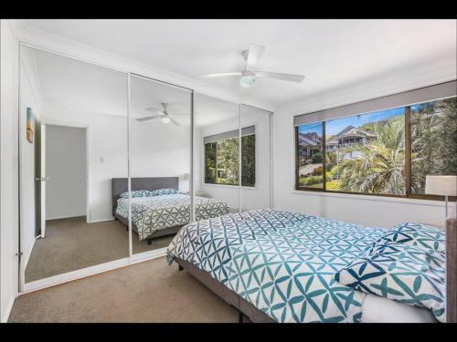 1 dormitorio con 2 camas y ventana grande en Gerroa Beach Family Headland Escape, en Gerroa