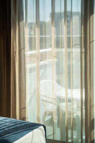 a bedroom with a window with curtains and a bed at Kapetanios Bay Hotel Protaras in Protaras