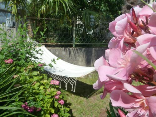 a hammock in a garden with pink flowers at Rose Apartments in Ičići